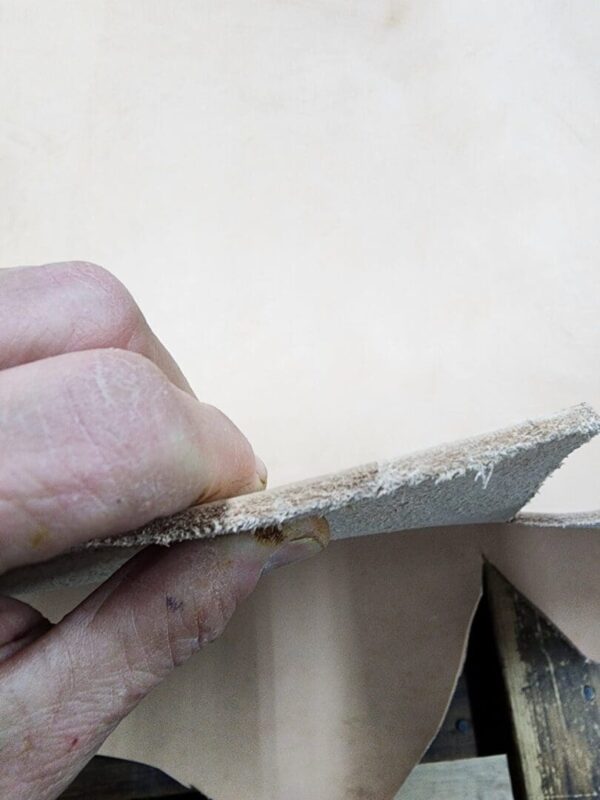 Hand holding a piece of leather.