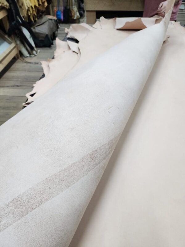Rolled leather sheets on wooden table.
