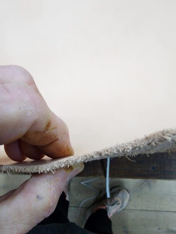 Person holding piece of thick leather.
