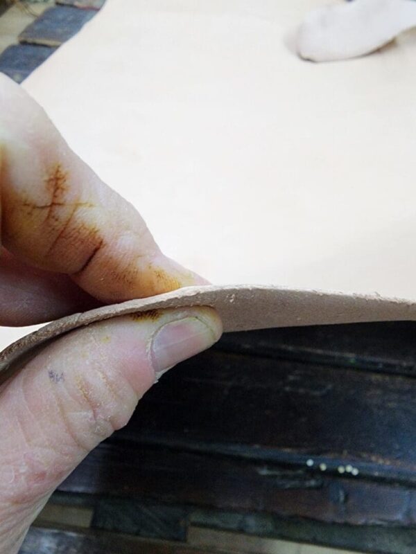 Hand holding a piece of leather.