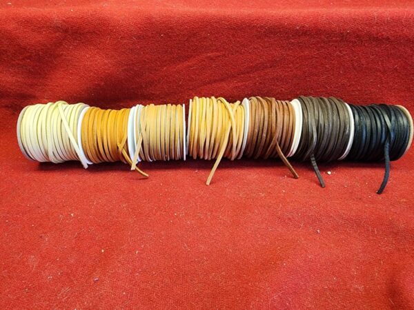 Colorful leather cords on red fabric background.