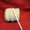 Roll of beige leather cord on red.