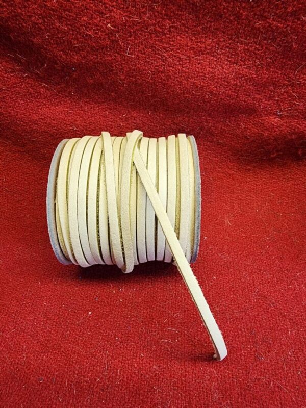 Roll of beige leather cord on red.