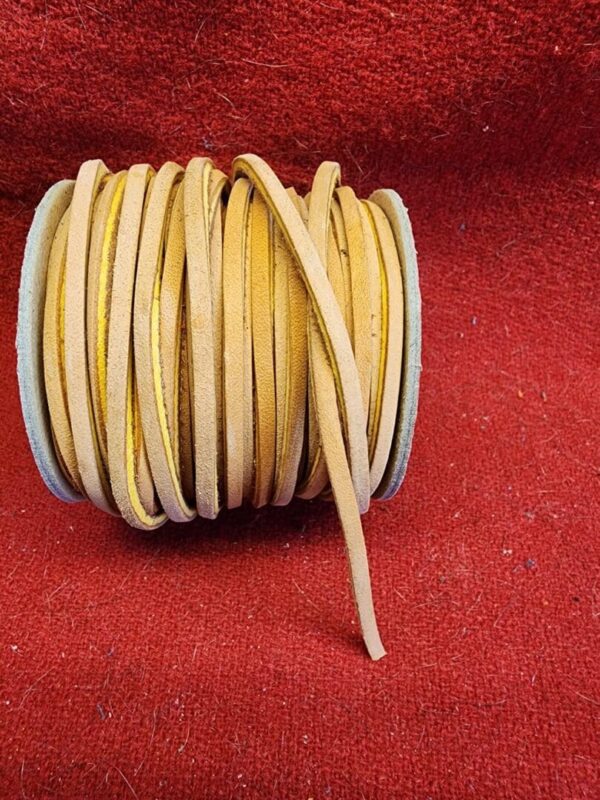 Yellow leather cord on red fabric background.