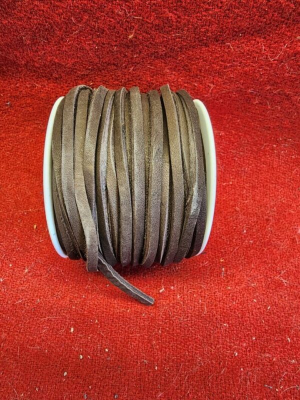 Brown leather cord spool on red fabric.