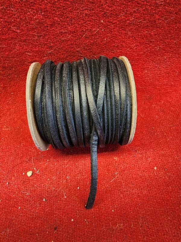 Black leather cord spool on red background.