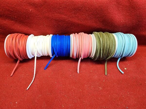 Colorful spools of string on red fabric.