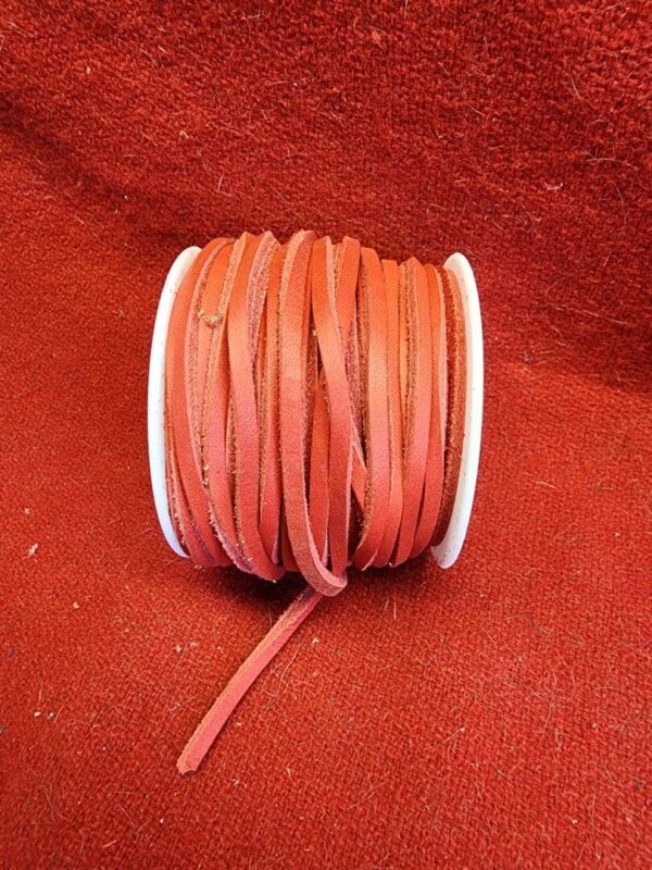 Red leather cord spool on red background.