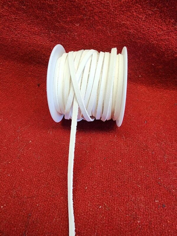 White ribbon spool on red fabric background.