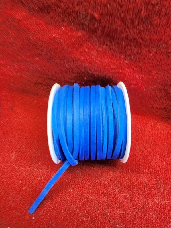 Blue ribbon spool on red fabric background.