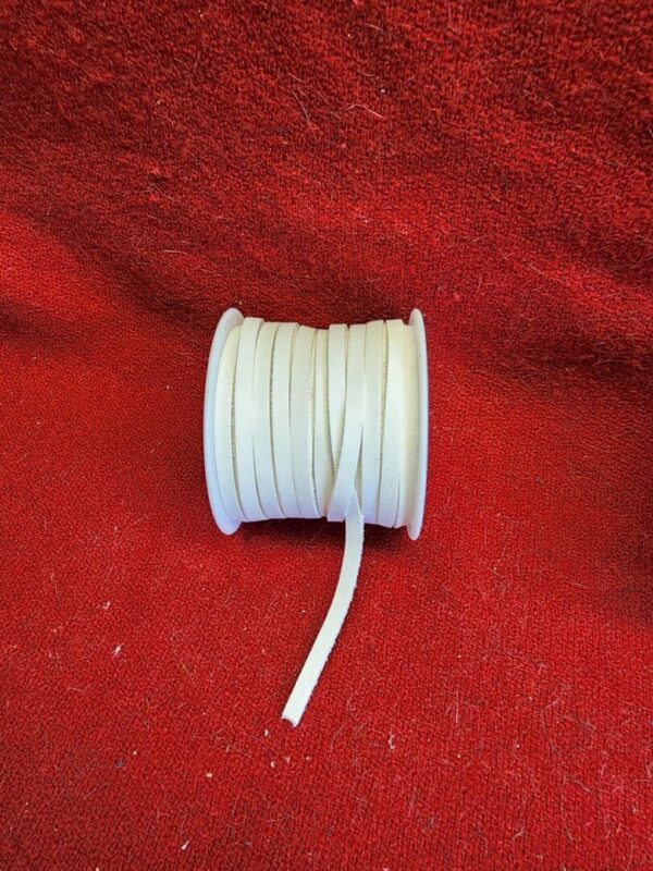 White ribbon spool on red fabric background.