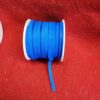 Blue ribbon spool on red fabric background.