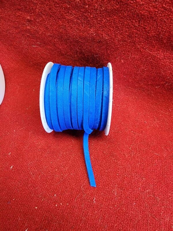 Blue ribbon spool on red fabric background.