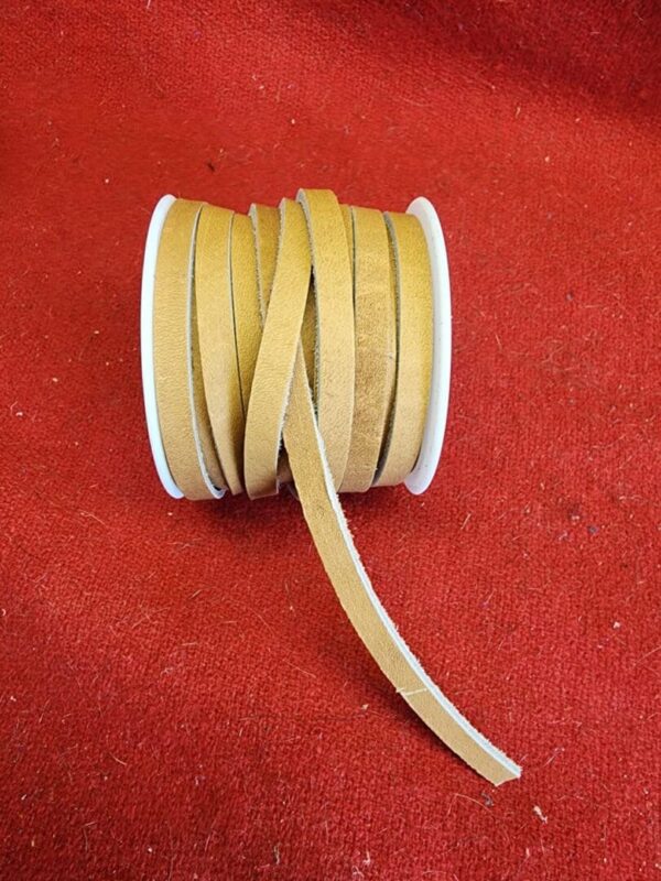 20240313_132704 Spool of brown leather strip on fabric.