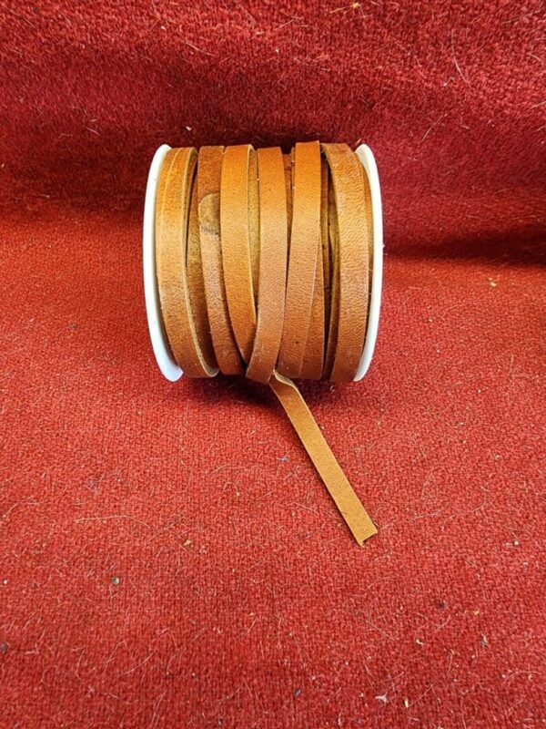 20240313_132712 Brown leather cord spool on red fabric.