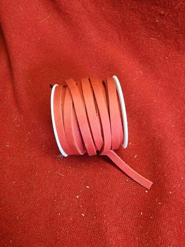 20240313_133623 Red ribbon spool on red fabric background.