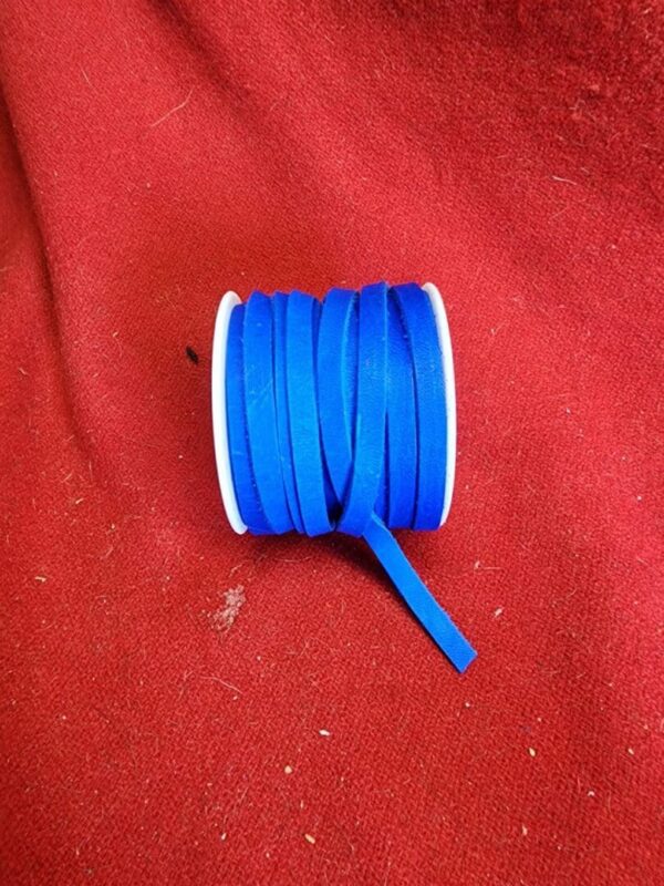 20240313_133627 Blue ribbon spool on red fabric background.