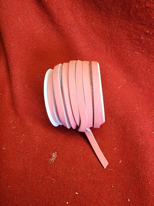 20240313_133630 Pink ribbon roll on red fabric background.