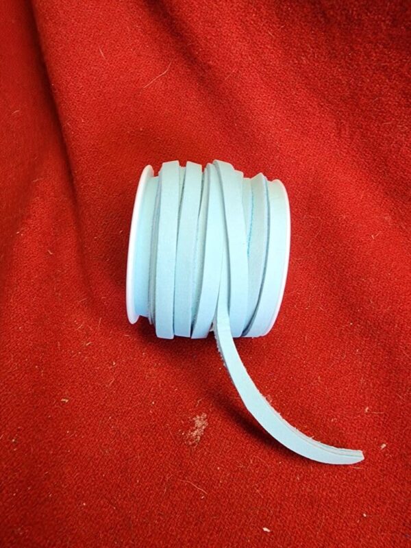 20240313_133634 White ribbon spool on red fabric background.