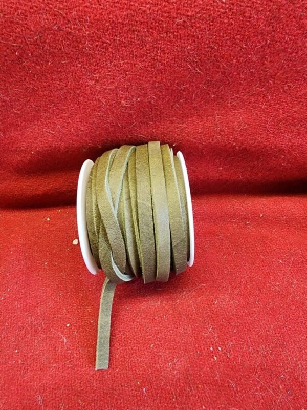 20240313_133636 Brown suede cord spool on red fabric.