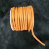 Orange leather cord spool on black surface.