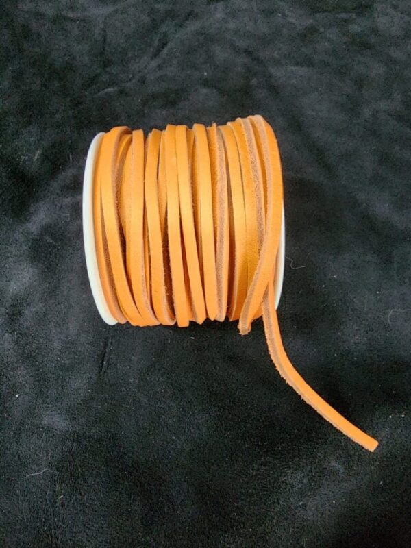 Orange leather cord spool on black surface.