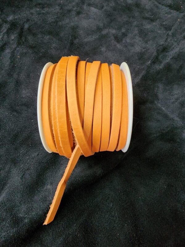 Orange ribbon spool on black fabric background.