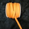 Orange ribbon spool on black background.