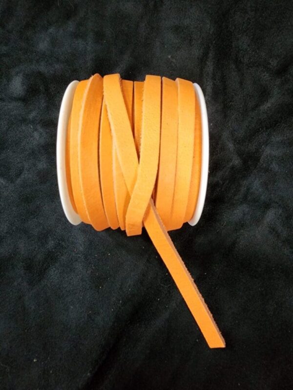 Orange ribbon spool on black background.