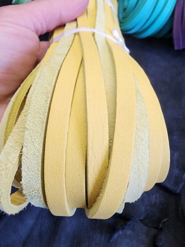 Hand holding yellow leather strips bundle.