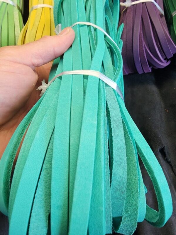 Hand holding bundle of colorful leather strips.