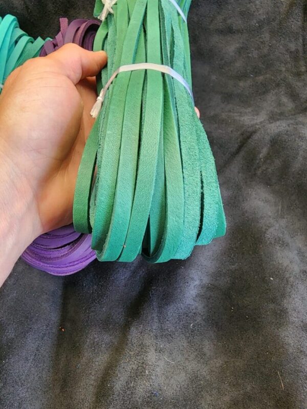 Hand holding green leather straps bundle.