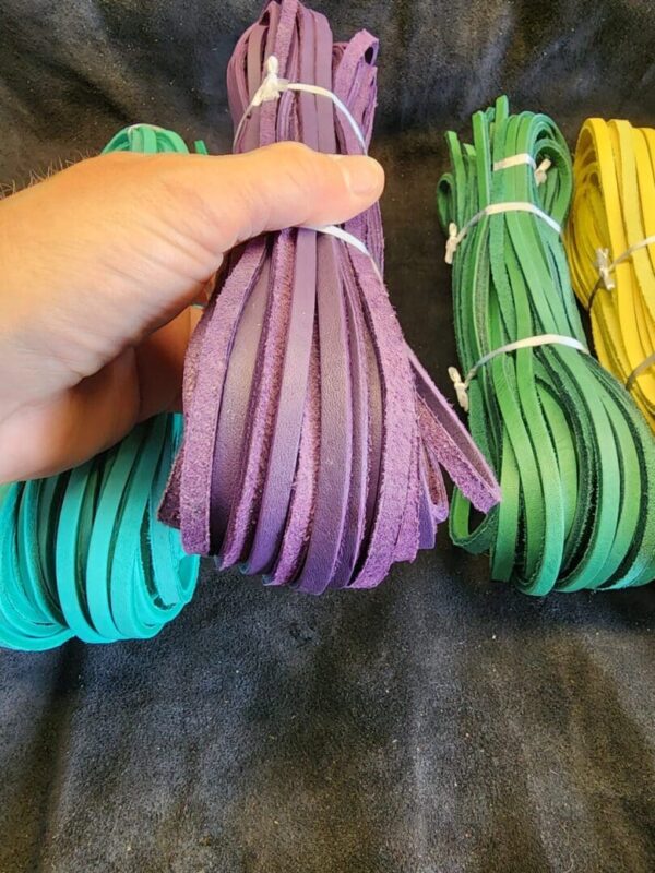 Hand holding purple leather strips, colorful background.