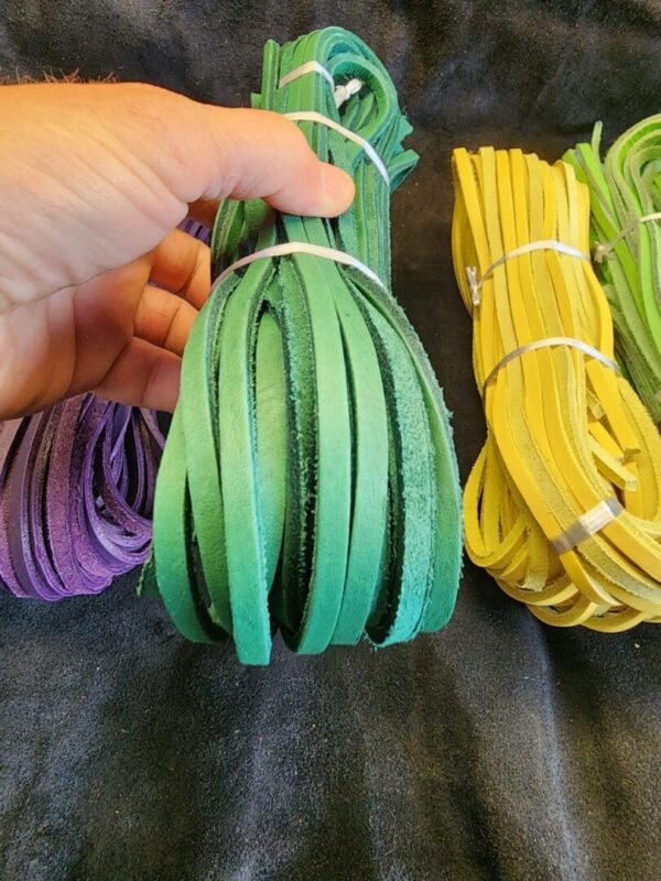 Hand holding colorful leather strips bundles.