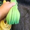 Hand holding green and yellow leather strips.