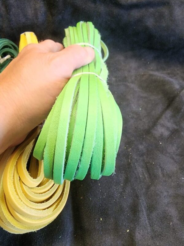 Hand holding green and yellow leather strips.