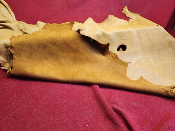 20240507_175419 Tan leather hide on red fabric background.