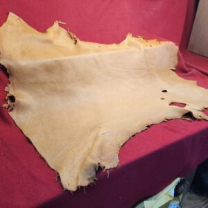 20240507_180019 Tanned leather hide on red fabric background.