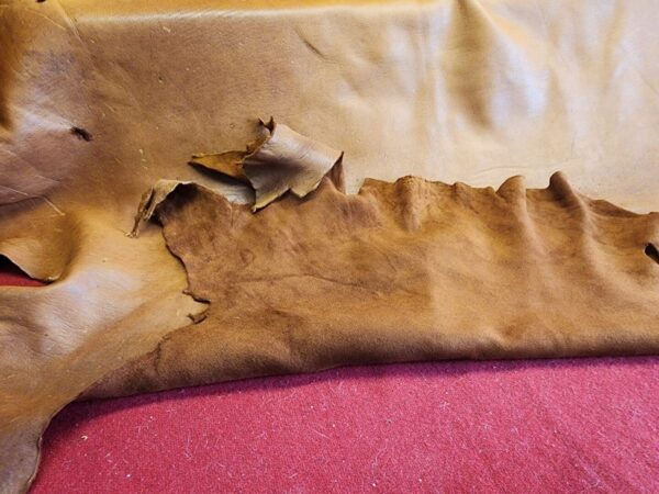 Torn brown leather on red fabric background.