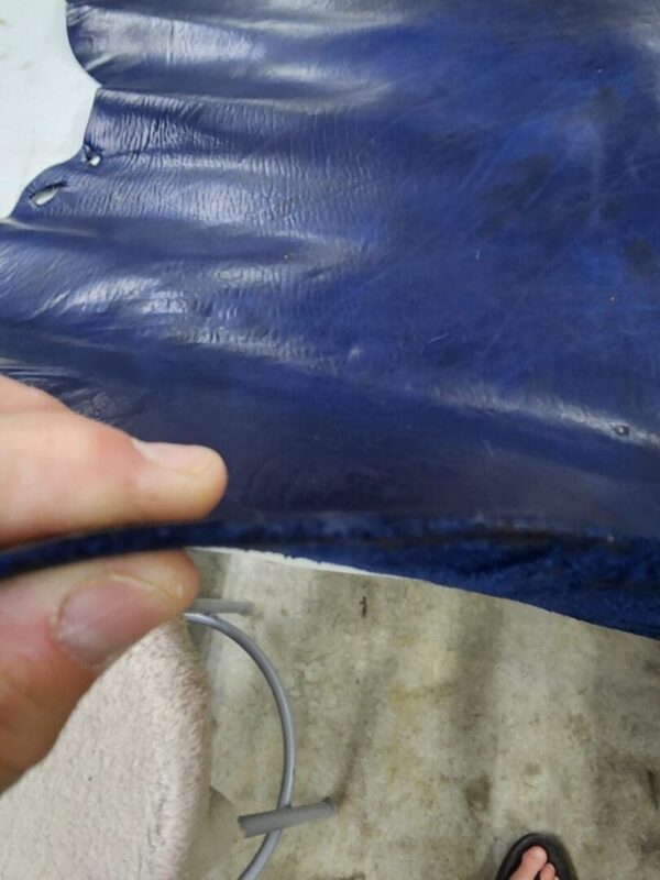 Hand holding a piece of blue leather.
