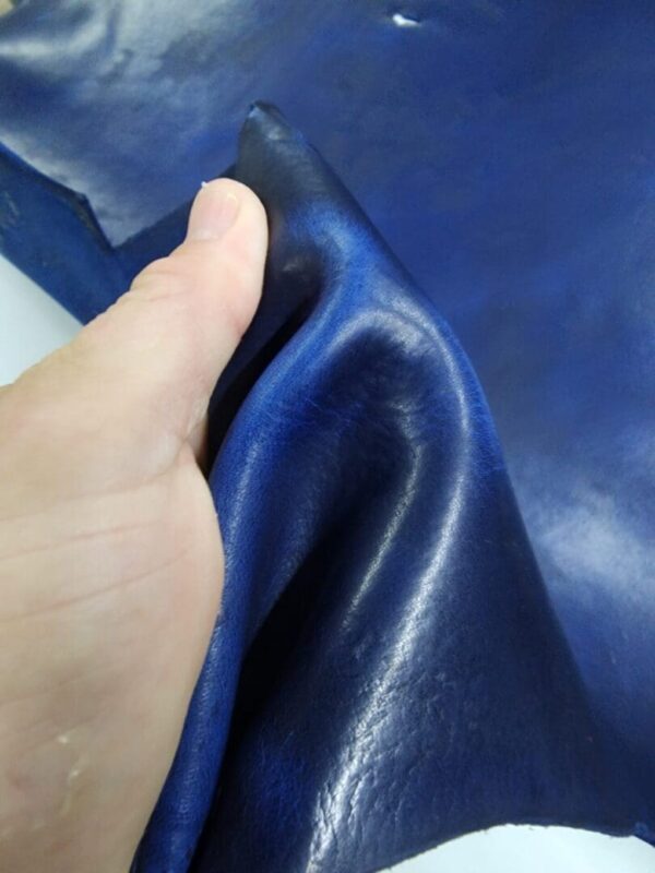 Hand holding a piece of blue leather.