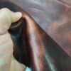 Hand holding dark brown leather material.