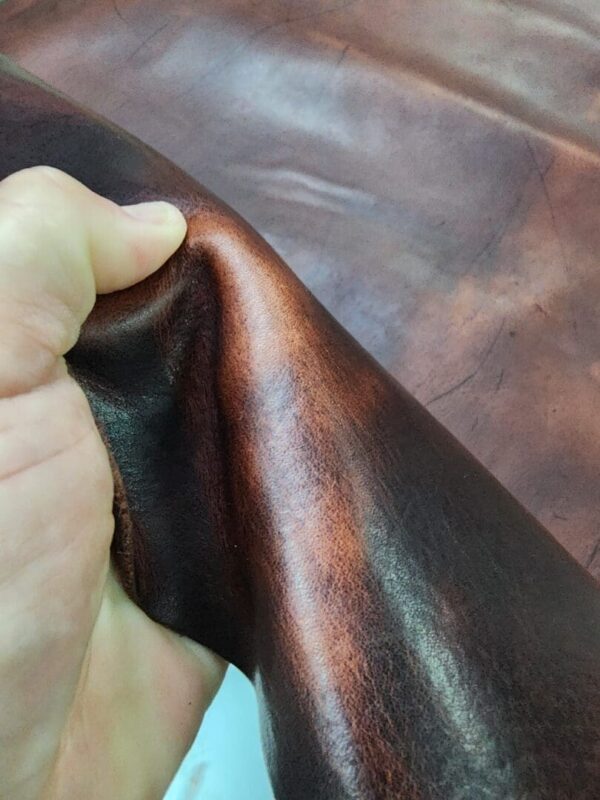 Hand holding dark brown leather material.
