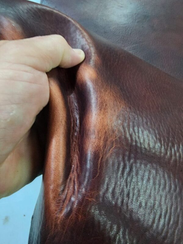 Hand holding a piece of dark leather.