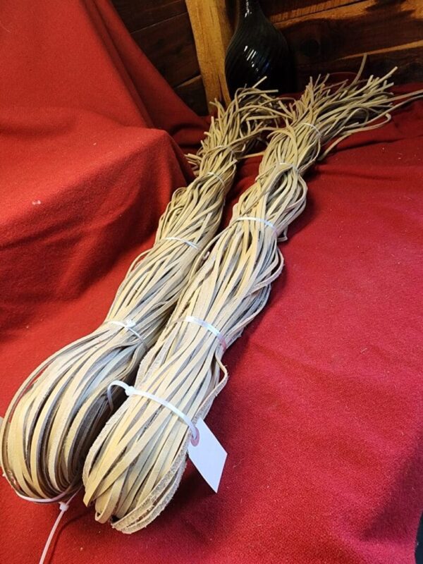 Bundles of light brown leather straps on red fabric.