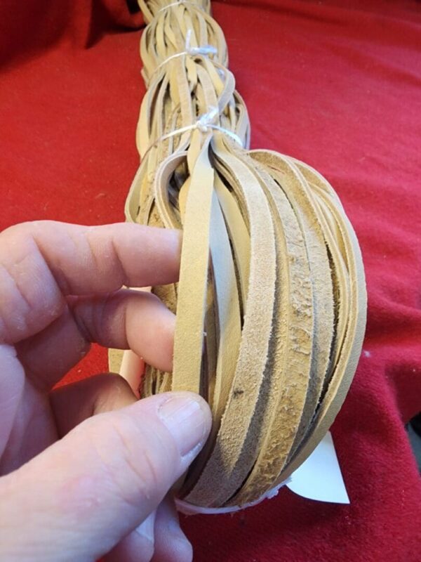 Hand holding a bundle of leather strips.