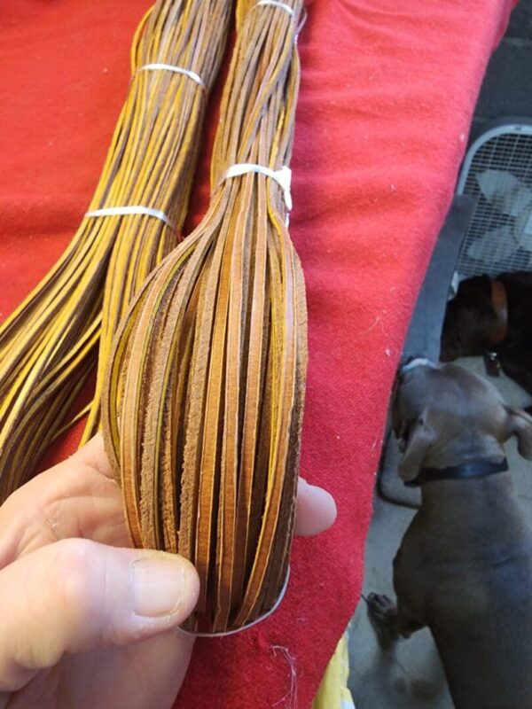 Hand holding brown leather strips on red cloth.