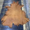 Tanned leather hide on wooden surface.