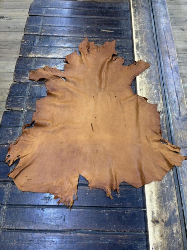 Tanned leather hide on wooden surface.