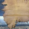 Tanned leather hide on wooden table.
